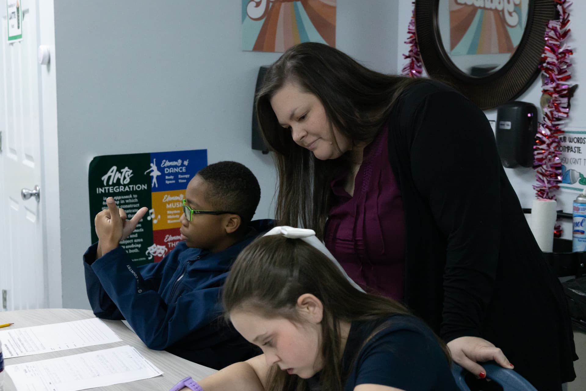 A teacher checking a student's work as he taps out sounds on his fingers
