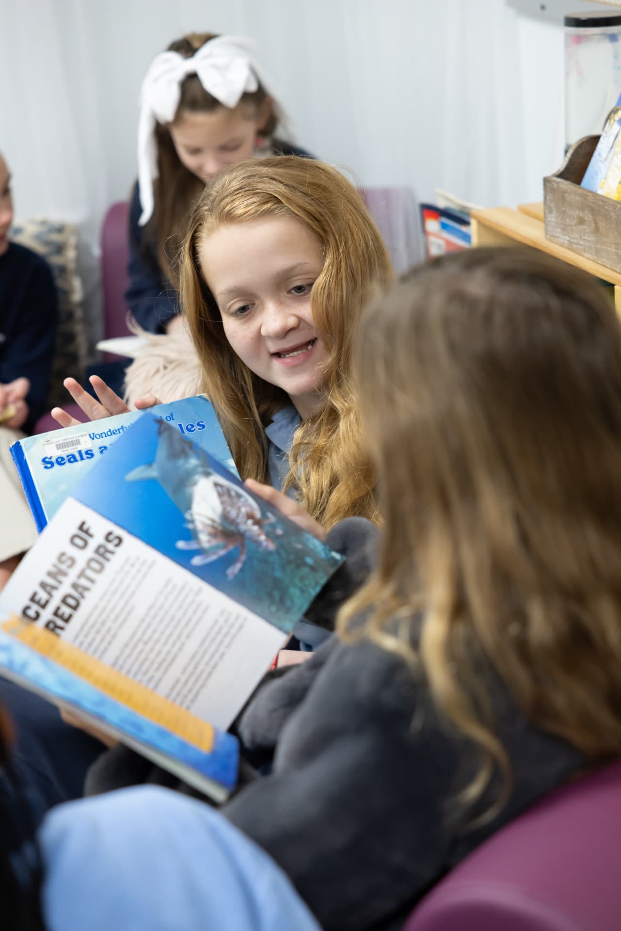 A student smiling while sharing an ocean nonfiction book with a classmate
