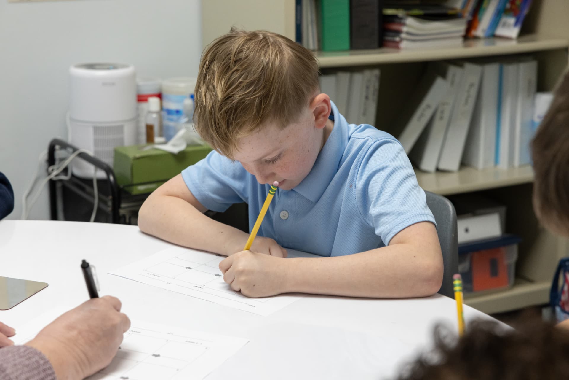 A student writing with a pencil during a one-on-one literacy session