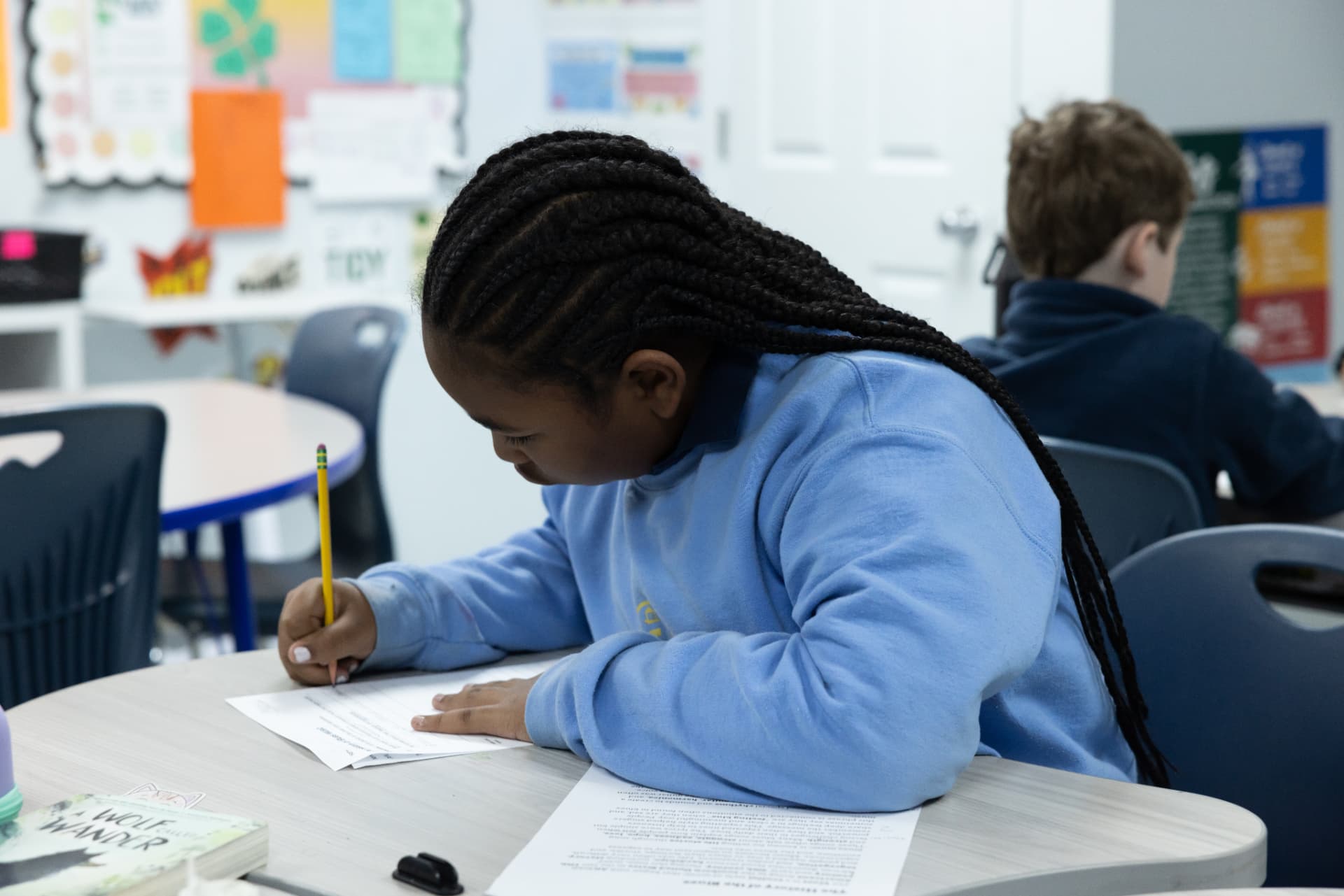 A student writing carefully on a worksheet during independent work time