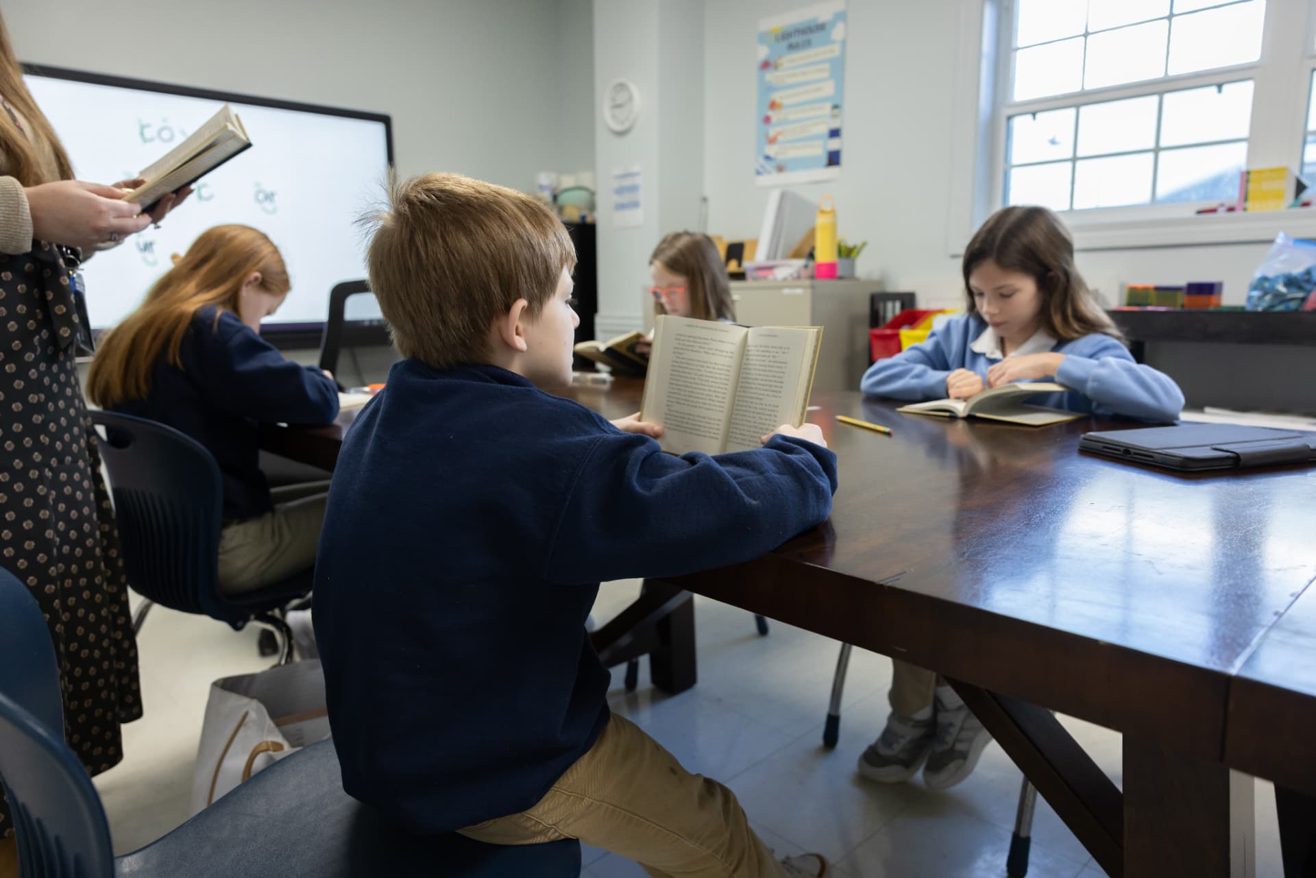 Students reading independently around a large wooden classroom table