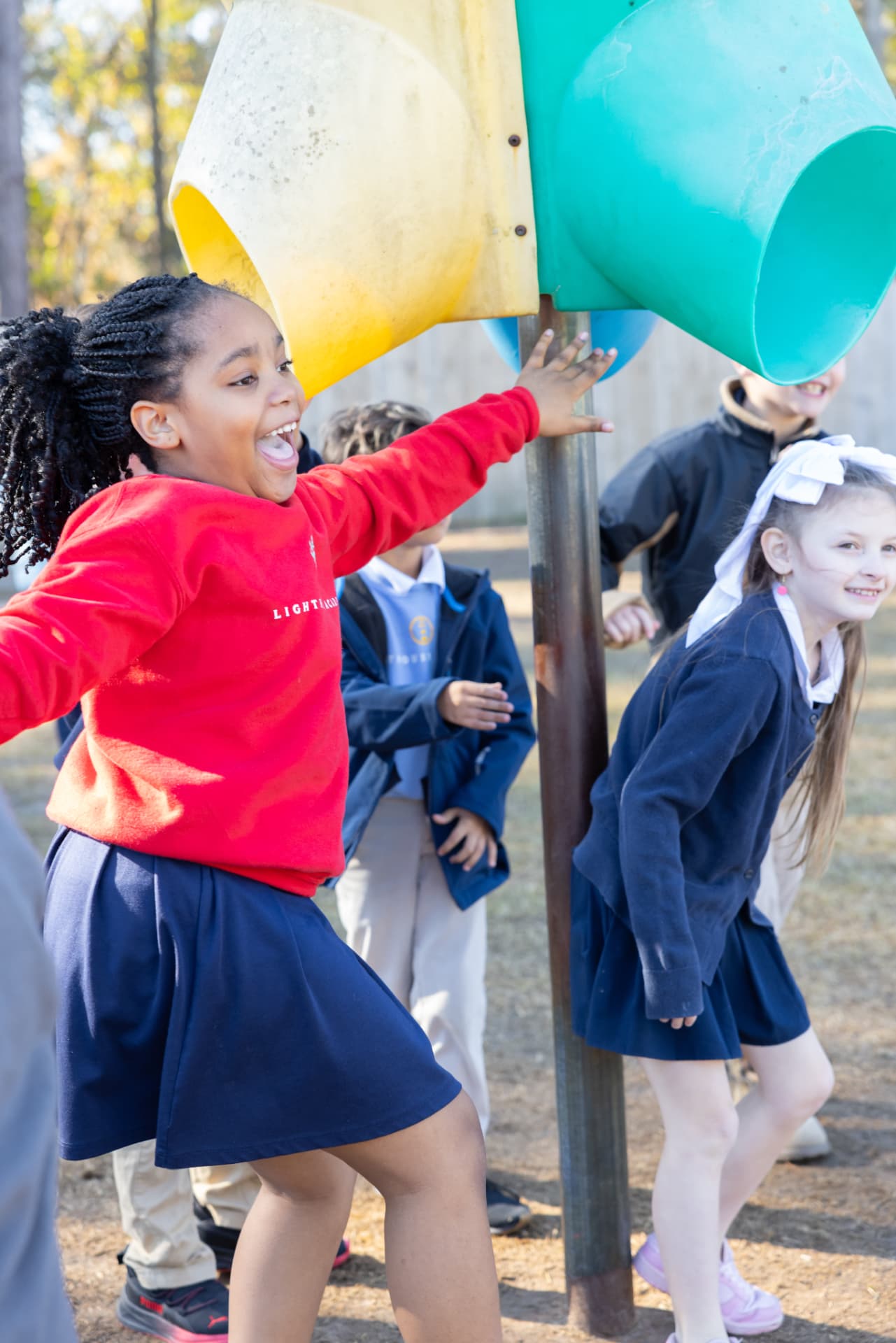 A student laughing on the playground with classmates at recess