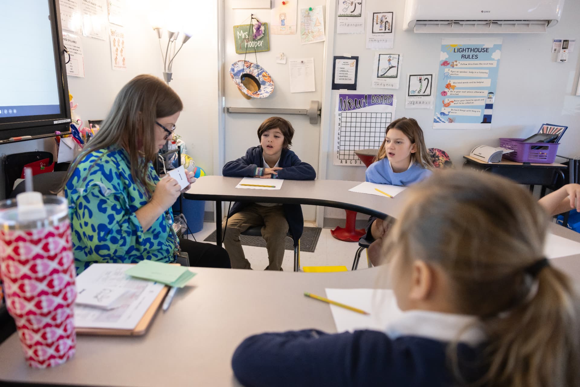 A teacher leading a small group phonics lesson with letter cards