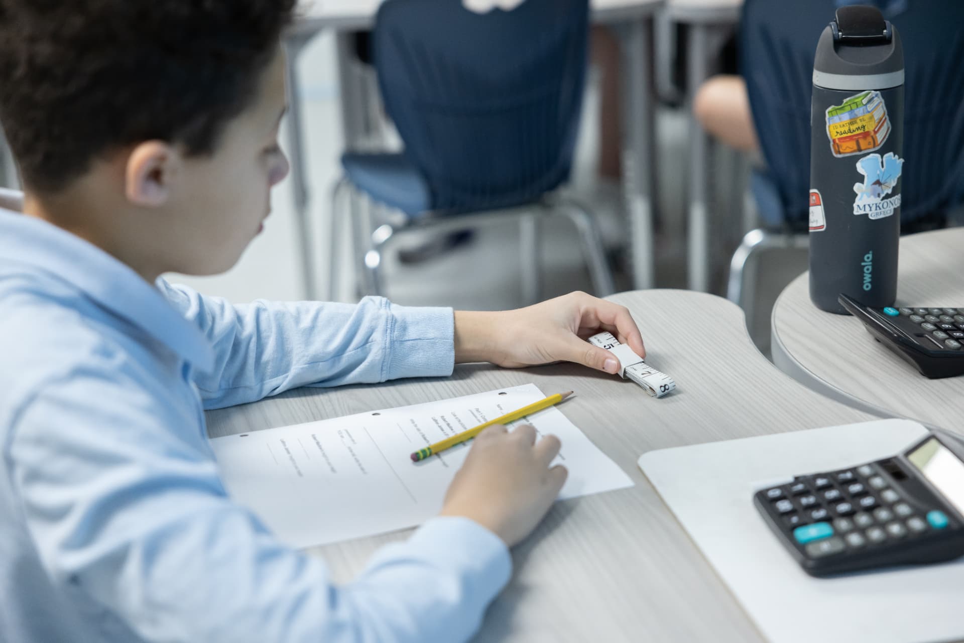 A student using a measuring tape on a hands-on math worksheet